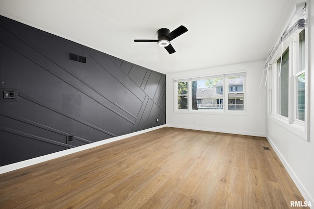 empty room with baseboards, ceiling fan, light wood-type flooring, and visible vents