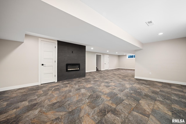 basement featuring visible vents, a fireplace, baseboards, stone finish floor, and recessed lighting