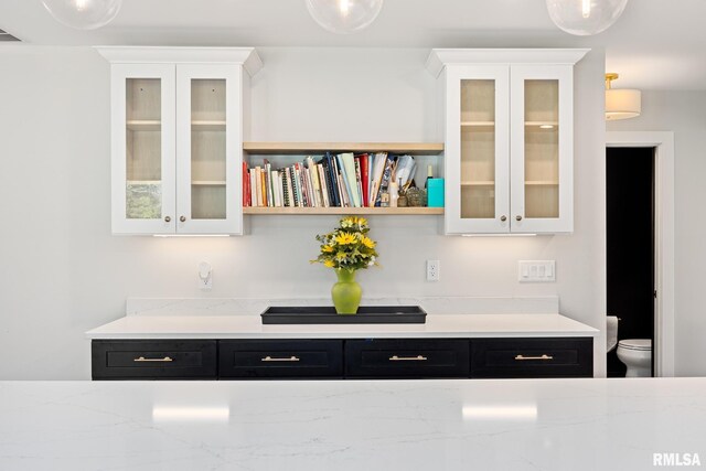 interior space featuring dark cabinets, white cabinetry, and glass insert cabinets