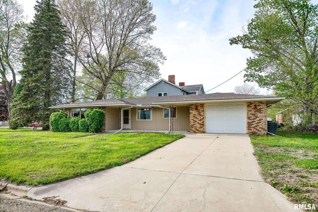 view of front facade featuring a chimney, brick siding, a front lawn, concrete driveway, and an attached garage
