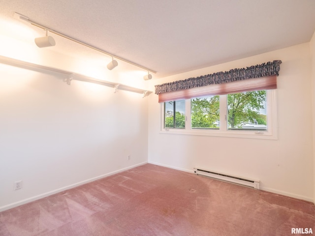 carpeted empty room with baseboards, baseboard heating, and rail lighting