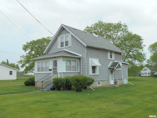 rear view of house with a shingled roof, a yard, and a chimney