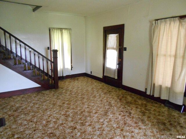 carpeted foyer entrance with baseboards and stairway