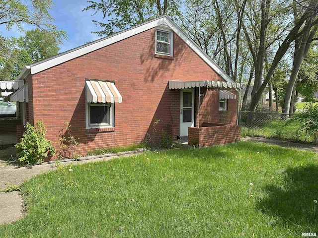exterior space with a lawn, fence, and brick siding