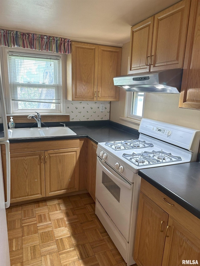 kitchen featuring under cabinet range hood, dark countertops, a sink, and gas range gas stove