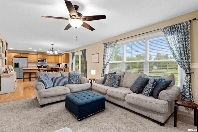 living room featuring light wood-type flooring, ceiling fan with notable chandelier, and recessed lighting