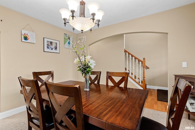 dining area with an inviting chandelier, arched walkways, baseboards, and stairway