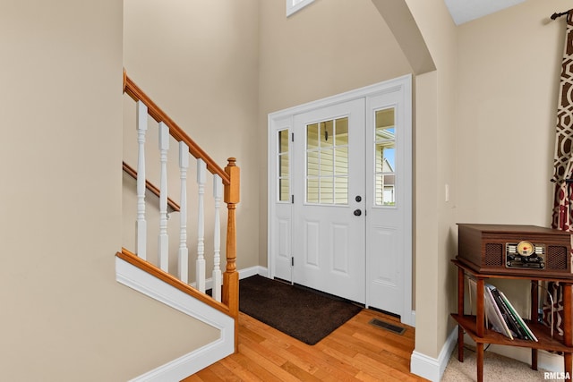 entrance foyer featuring visible vents, arched walkways, wood finished floors, and a wealth of natural light