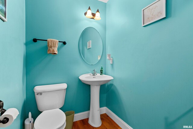 bathroom featuring a sink, baseboards, toilet, and wood finished floors