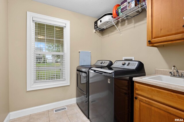 clothes washing area featuring visible vents, baseboards, cabinet space, independent washer and dryer, and light tile patterned floors