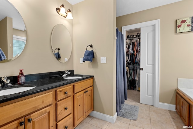 full bath with double vanity, a sink, baseboards, and tile patterned floors