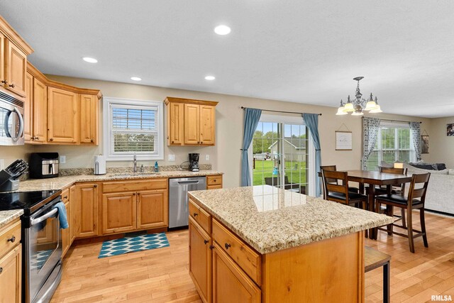 kitchen with appliances with stainless steel finishes, a sink, an inviting chandelier, and light wood-type flooring
