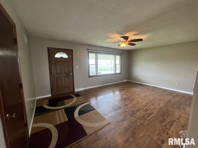 entryway featuring ceiling fan, a textured ceiling, visible vents, baseboards, and dark wood-style floors