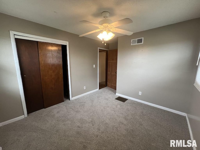 unfurnished bedroom featuring carpet flooring, ceiling fan, baseboards, visible vents, and a closet