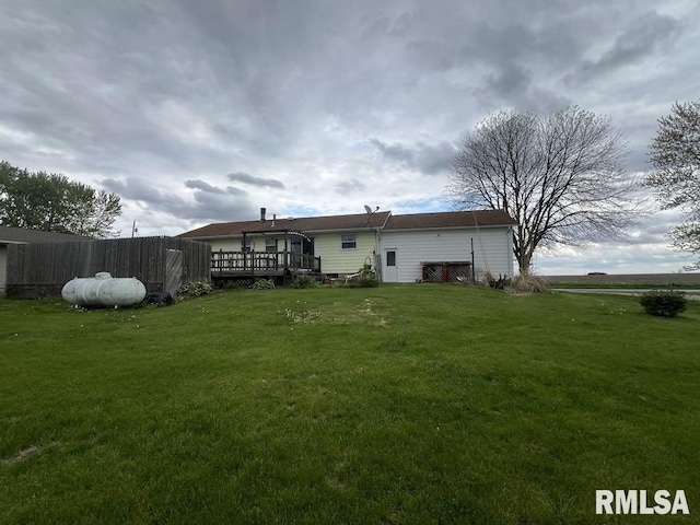 rear view of property featuring fence, a wooden deck, and a yard