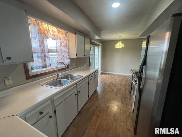 kitchen featuring wood finished floors, a sink, light countertops, freestanding refrigerator, and white cabinetry