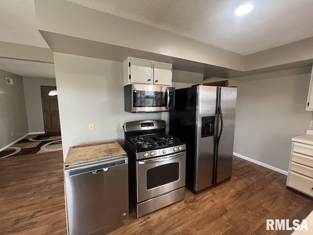 kitchen with dark wood-type flooring, baseboards, appliances with stainless steel finishes, and white cabinets