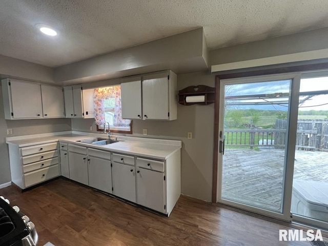 kitchen with light countertops, white cabinetry, a textured ceiling, and a sink