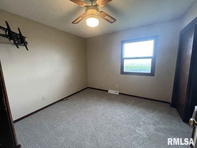 carpeted empty room with baseboards, visible vents, and ceiling fan