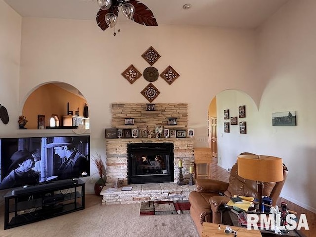 24211 N Carver Rd, Canton, IL 61520 - living area with a ceiling fan, arched walkways, a stone fireplace, and a towering ceiling