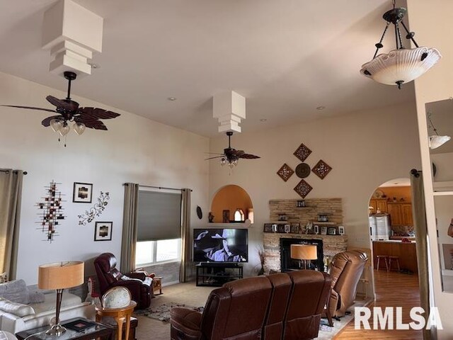 24211 N Carver Rd, Canton, IL 61520 - living area with ceiling fan, a stone fireplace, arched walkways, a towering ceiling, and light wood-style floors
