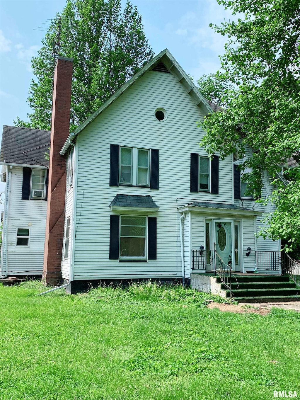 view of front facade featuring a chimney, a wooden deck, and a front yard