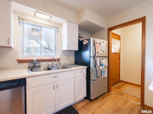 kitchen with light countertops, white cabinetry, a sink, light wood finished floors, and stainless steel appliances