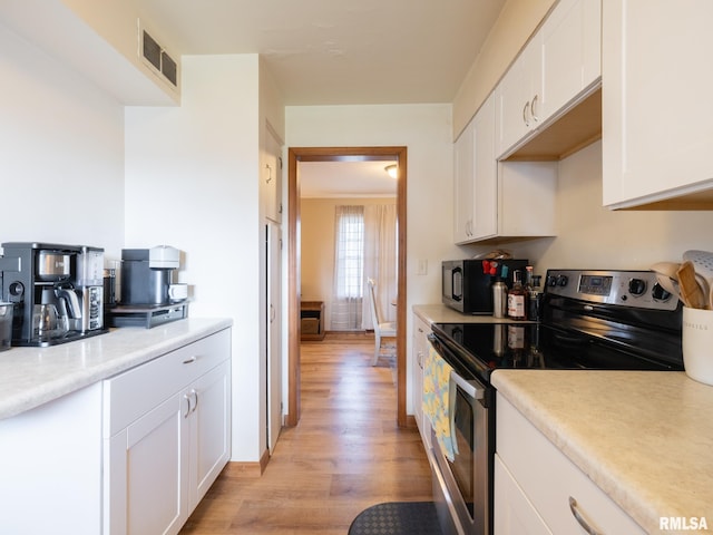kitchen featuring visible vents, electric stove, white cabinetry, and light wood-type flooring