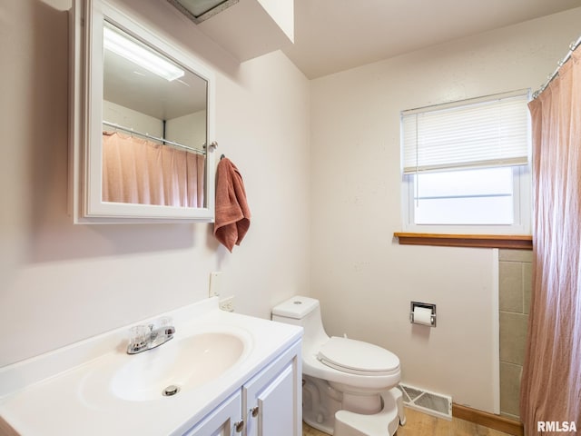 bathroom with vanity, toilet, wood finished floors, and visible vents