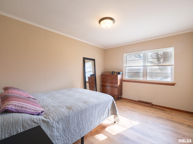 bedroom featuring crown molding, baseboards, light wood finished floors, and visible vents