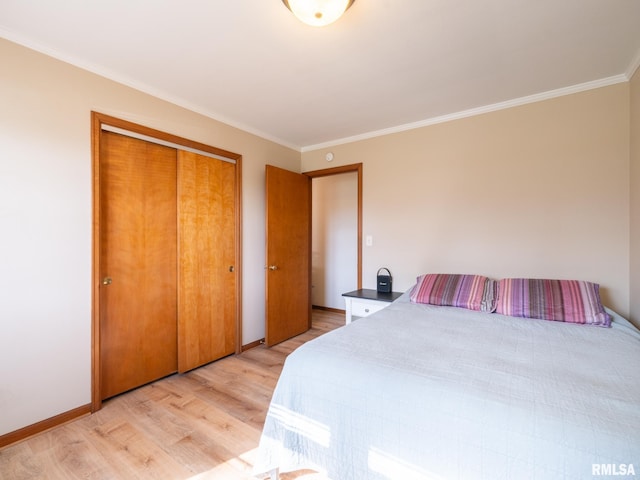 bedroom with crown molding, baseboards, light wood-style flooring, and a closet