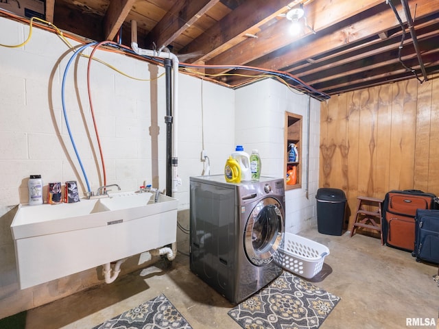 clothes washing area with laundry area, washer and clothes dryer, a sink, and concrete block wall