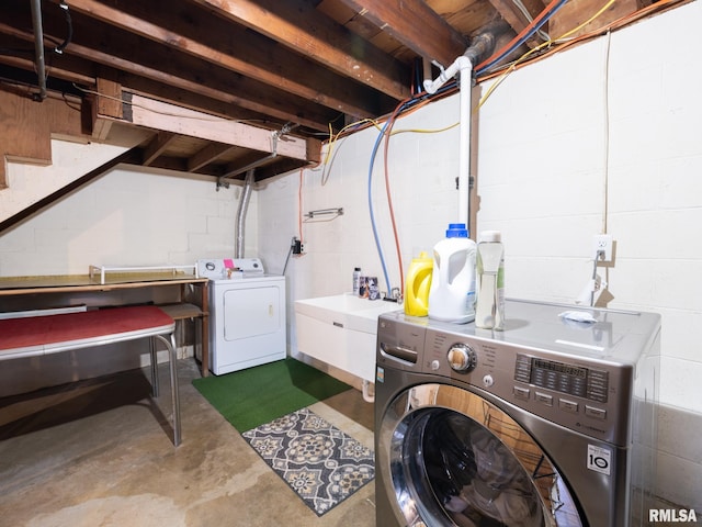 laundry room with laundry area, a sink, washer and dryer, and concrete block wall