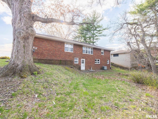 view of side of home with a lawn, brick siding, and central AC
