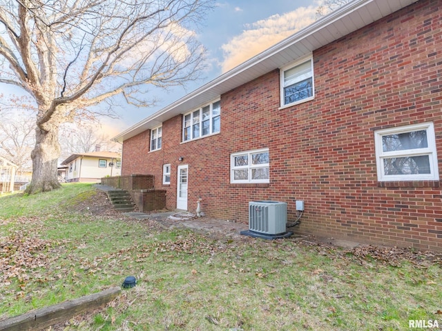 rear view of property featuring brick siding and central AC unit