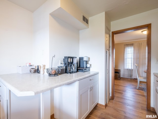 kitchen featuring light countertops, light wood-style flooring, white cabinetry, a peninsula, and visible vents