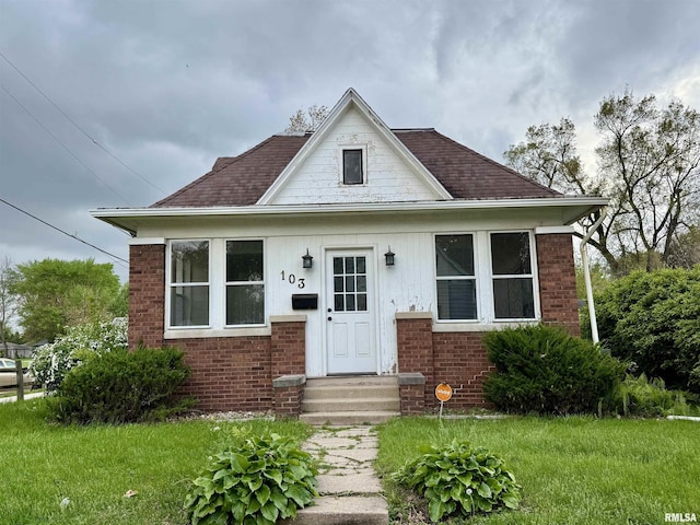bungalow with brick siding and a front lawn