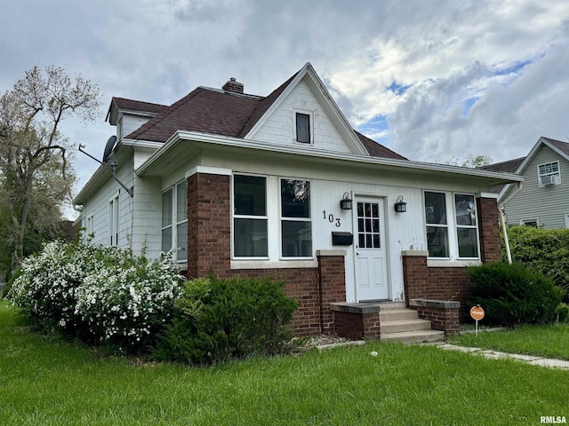 bungalow-style house with brick siding, a front lawn, and a chimney
