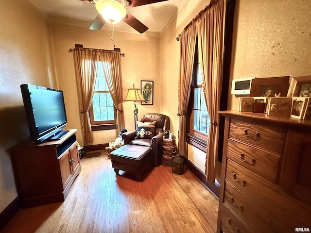 sitting room with crown molding, light wood-style flooring, ceiling fan, and baseboards