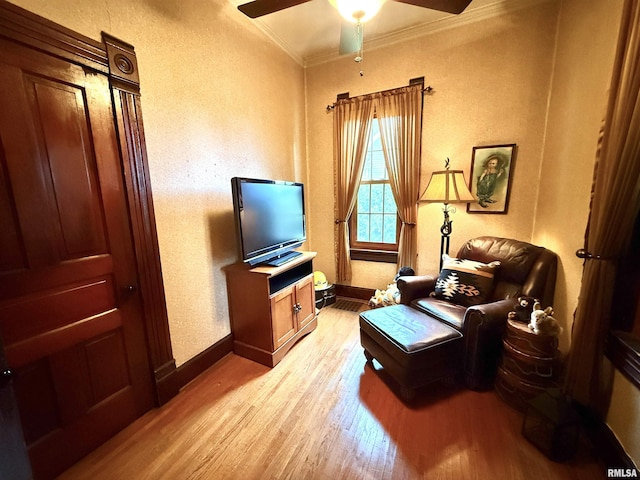 living area featuring crown molding, ceiling fan, baseboards, and light wood-type flooring
