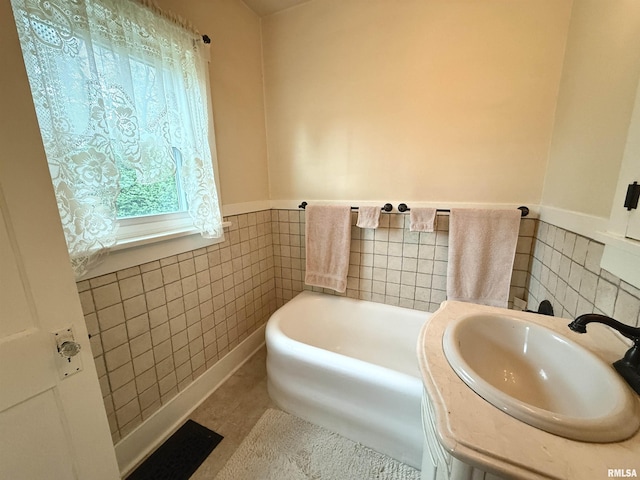 full bath featuring a sink, tile walls, a wainscoted wall, and a bath