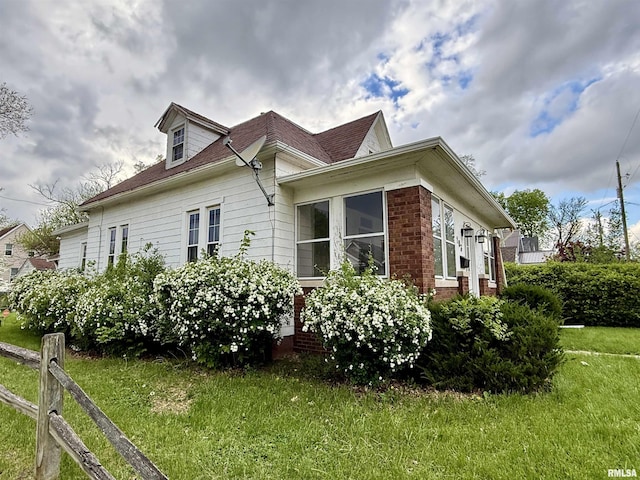 view of side of home featuring a lawn and a shingled roof