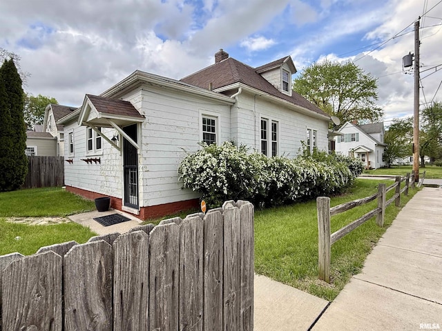 view of side of property with a yard, fence, and a chimney