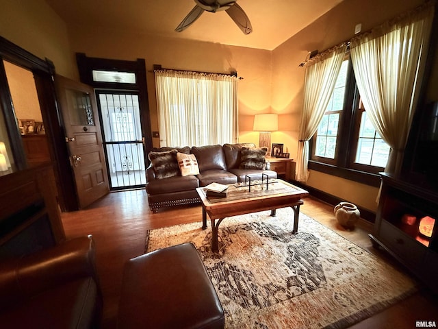 living area featuring a ceiling fan, wood finished floors, and vaulted ceiling