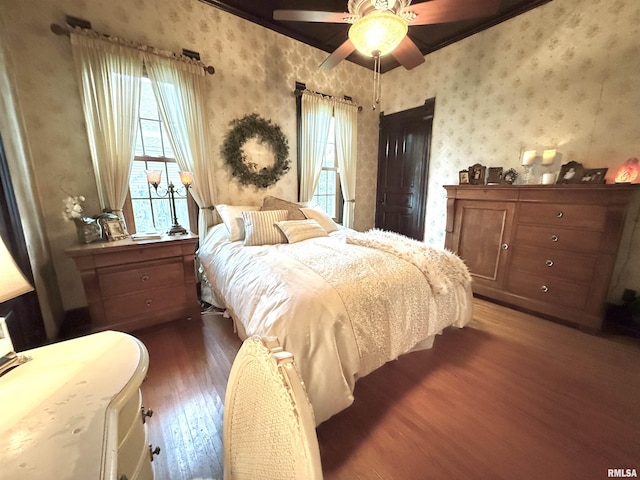 bedroom with ceiling fan, wood finished floors, and wallpapered walls