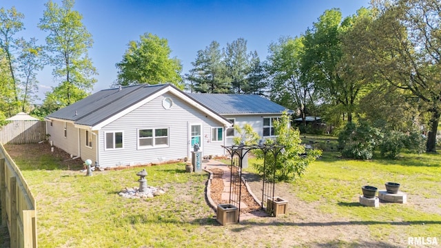 back of house featuring a yard, fence, and metal roof