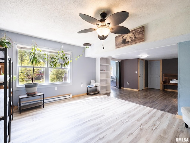 interior space featuring ceiling fan, a textured ceiling, wood finished floors, and a baseboard heating unit