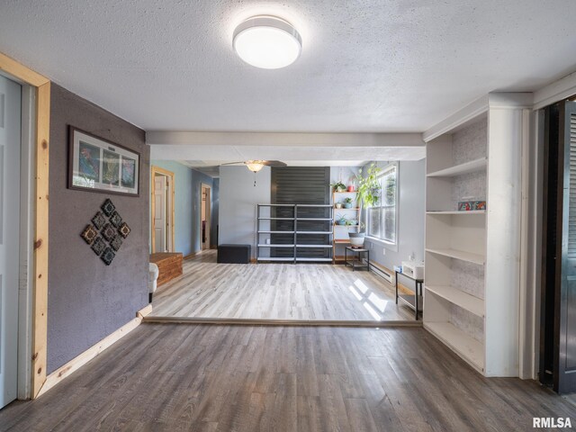 interior space with baseboards, a ceiling fan, a textured ceiling, and wood finished floors