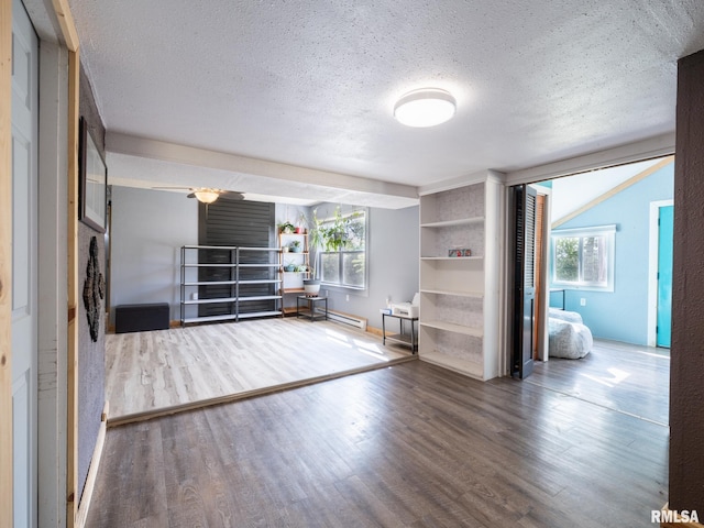 interior space with a textured ceiling, baseboard heating, and wood finished floors