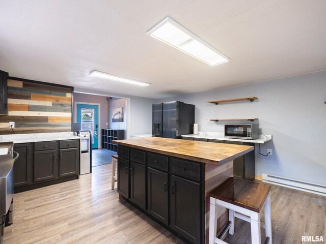 kitchen featuring wood counters, open shelves, light wood finished floors, dark cabinetry, and refrigerator with ice dispenser